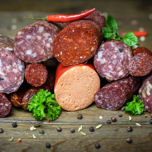 Eine variierte Ansammlung verschiedener Salami und Rohwürsten, dekoriert mit Kräutern.