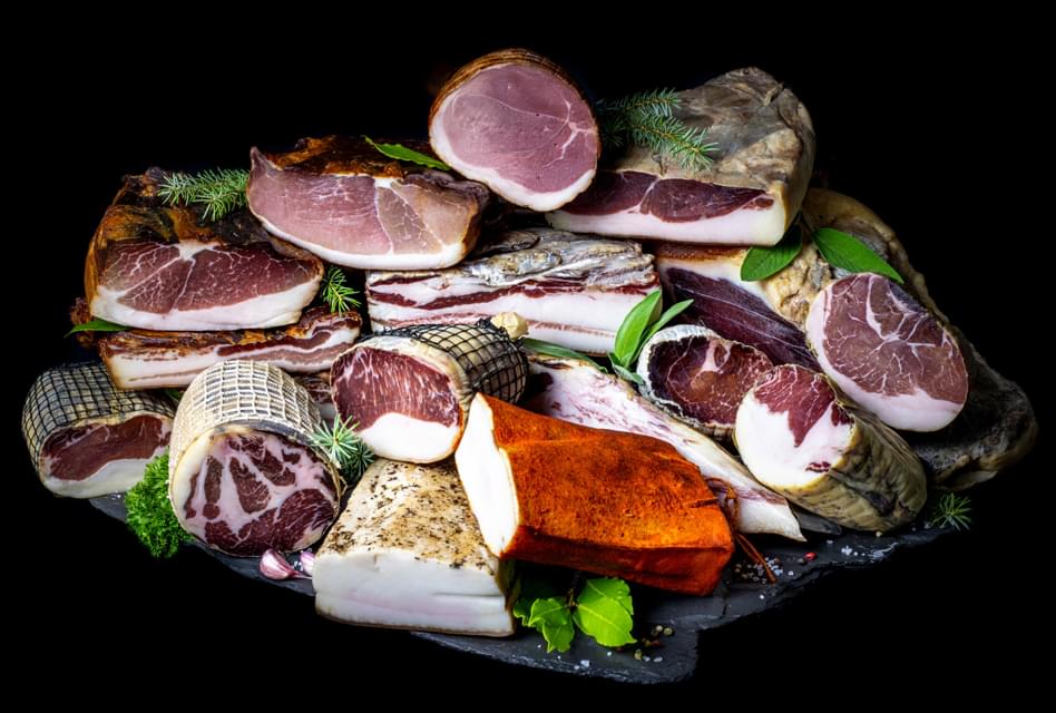 Eine reiche Palette an Mangalitza-Schweinespezialitäten, dekoriert mit Kräutern.